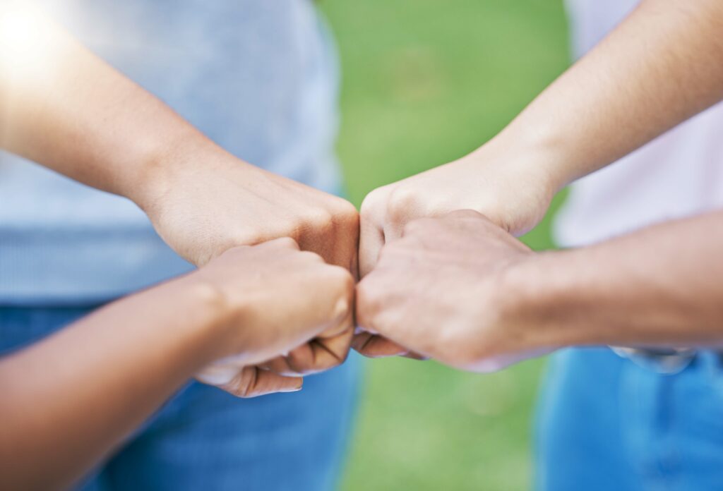 People, hands and fist bump in collaboration for community, partnership or trust together in the ou